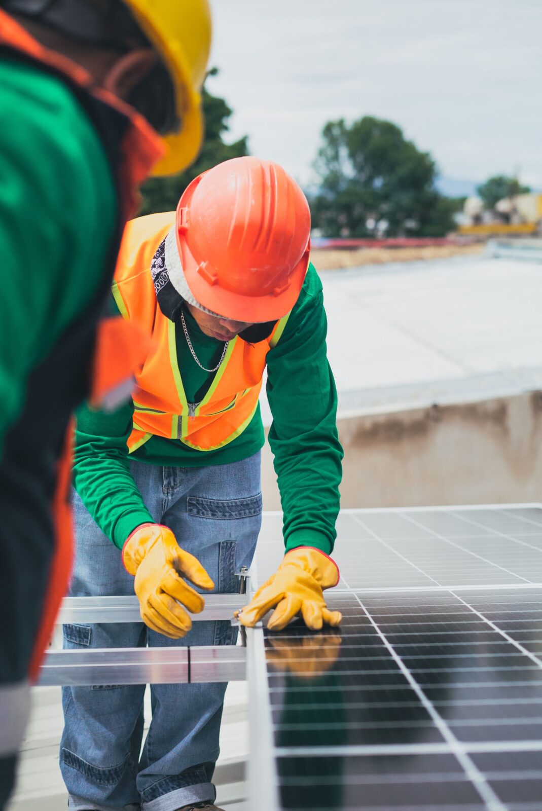 Tecnico con casco e guanti da lavoro installa i moduli di un impianto fotovoltaico