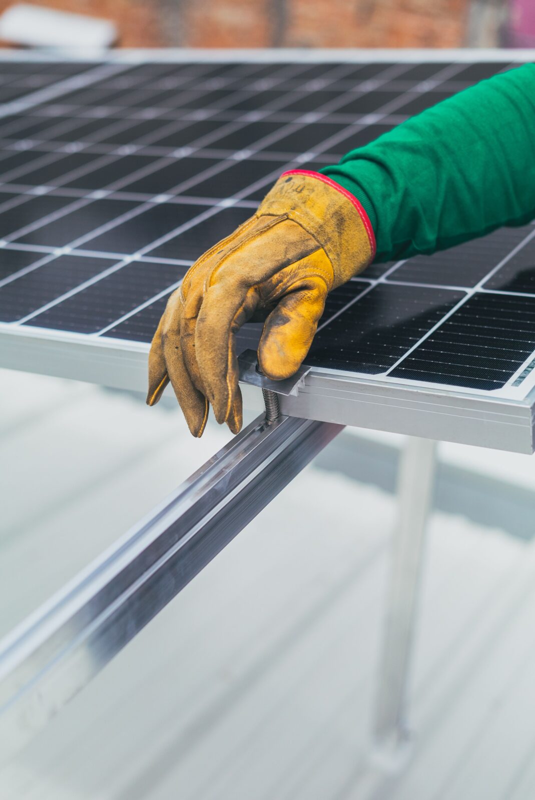 Dettaglio del fissaggio di un modulo fotovoltaico con guanti da lavoro